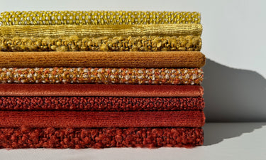 Adda Textiles Image of Textural Upholstery Fabrics Stacked on top of each other in orange and yellow 